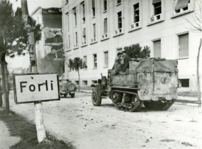 L'immagine simbolo della Liberazione di Forlì. La via Emilia, il collegio aeronautico Bruno Mussolini con i segni di bombardamenti, l'ingresso in città degli alleati. Fotografia tratta dal volume "1944: dolore e terrore" edito dal Comune di Forlì.