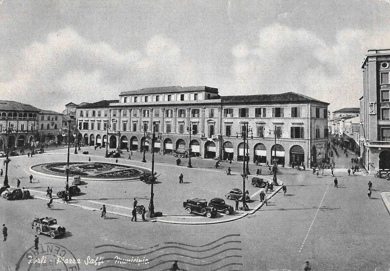 Alcuni segni della guerra in piazza Saffi. Nell'immagine mancano: la statua di Saffi distrutta da un bombardamento degli alleati, la torre civicadietro il palazzo comunale e sulla destra la torretta degli uffici statali, entrambe minate dai tedesci in ritirata. Cartolina spedita nel 1955. Raccolta privata.